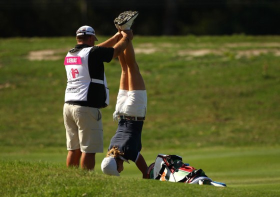 Giulia Sergas realiza estiramientos de espalda con la ayuda de su caddie.