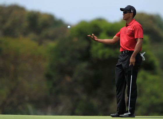 Tiger Woods entrega su bola al caddie en un green durante la última vuelta en Sídney.