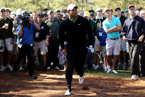 Tiger Woods corre para ver su segundo golpe en el hoyo 1 desde los árboles.