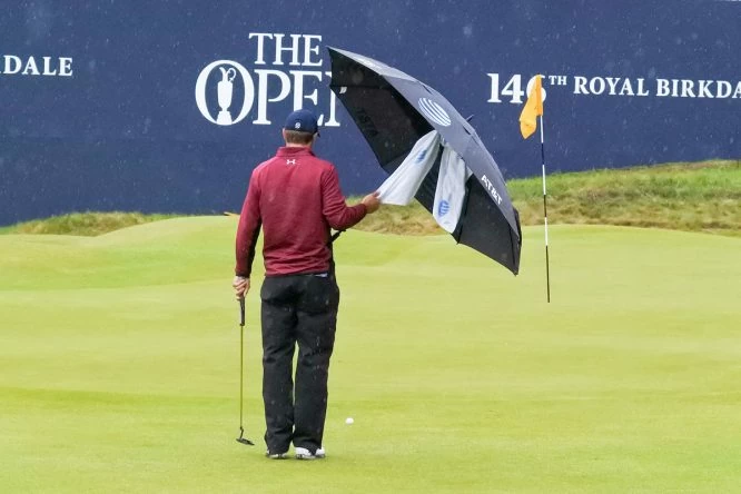 Jordan Spieth sostiene el paraguas bajo la lluvia en el 18. © Golffile | Fran Caffrey