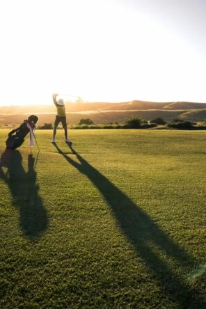 Persona en un campo de golf de hierba verde balanceando un palo al lado de una bolsa de golf