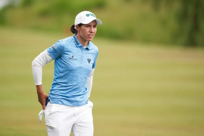 Carlota Ciganda camina por un campo de golf con la publicidad de Golf Saudi