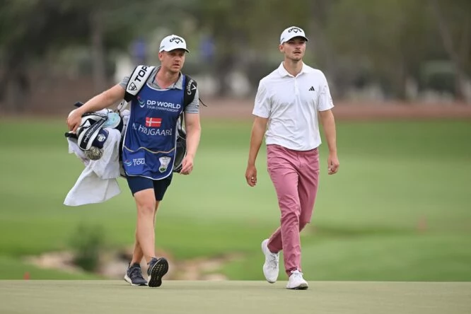 Nicolai Hojgaard of Denmark walks with his caddie, Christian Christensenon the 18th green during Day One of the DP World Tour Championship on the Earth Course at Jumeirah Golf Estates on November 16, 2023 in Dubai, United Arab Emirates. (Photo by Ross Kinnaird/Getty Images)
