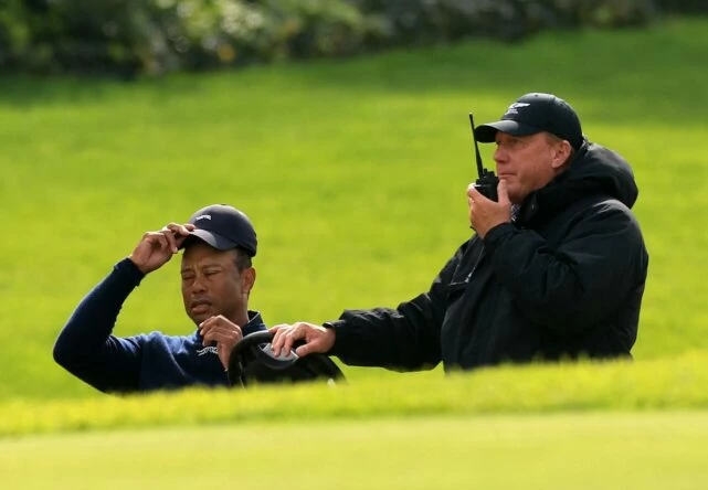 Tiger Woods, acompañado por un árbitro en un buggie justo después de tomar la decisión de retirarse del Genesis.