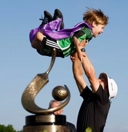 Peter Malnati sostiene en el aire a su hijo a la espera de recibir el trofeo de campeón del Valspar.