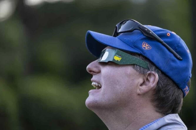 Un aficionado observa el eclipse ayer en la primera jornada de la semana del Masters de Augusta.